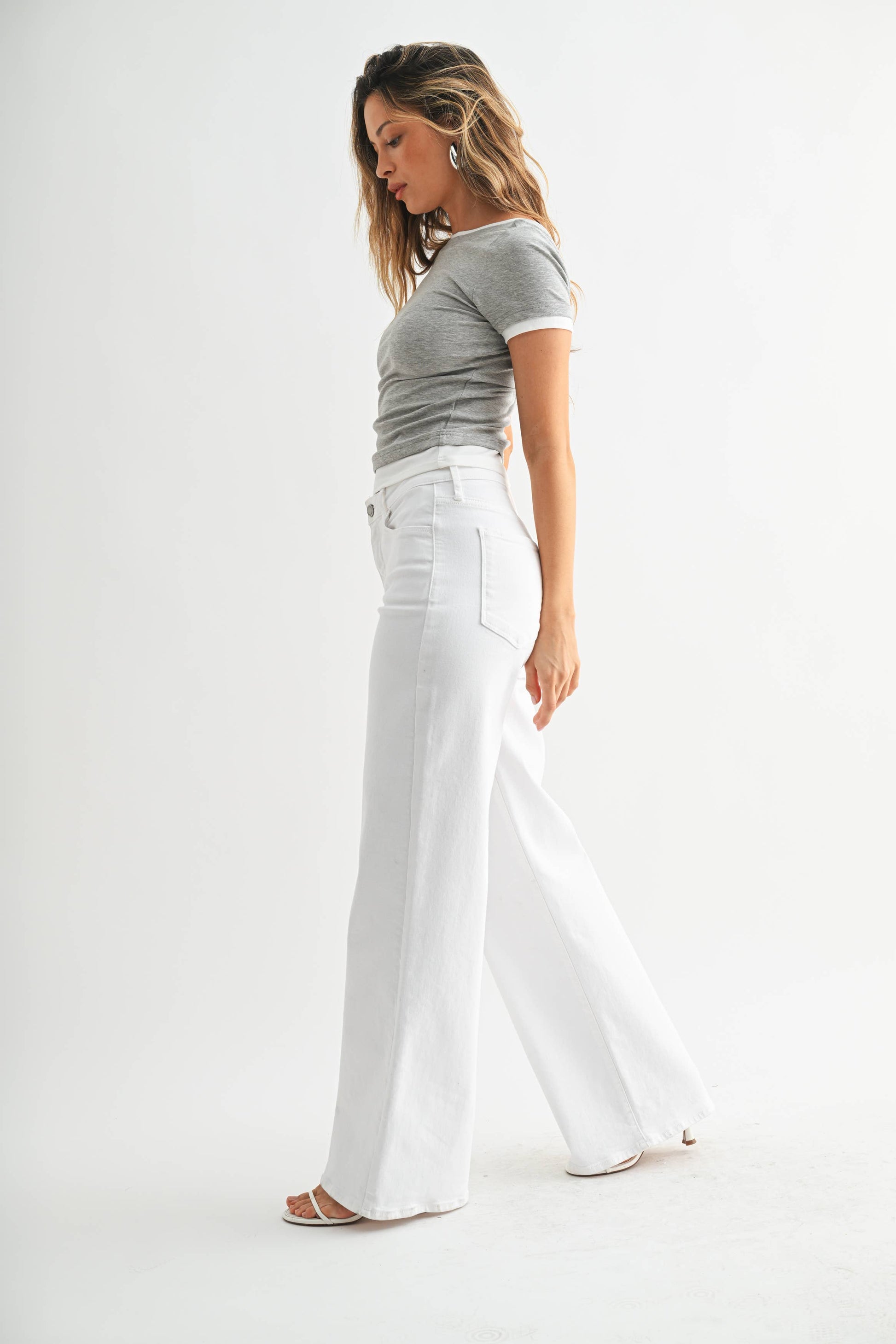 Woman wearing a gray t-shirt and white pants on a white background