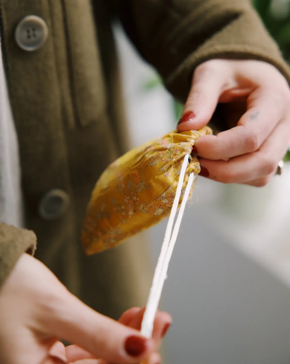 Person peeling a yellow fruit with a stick, wearing a green coat.