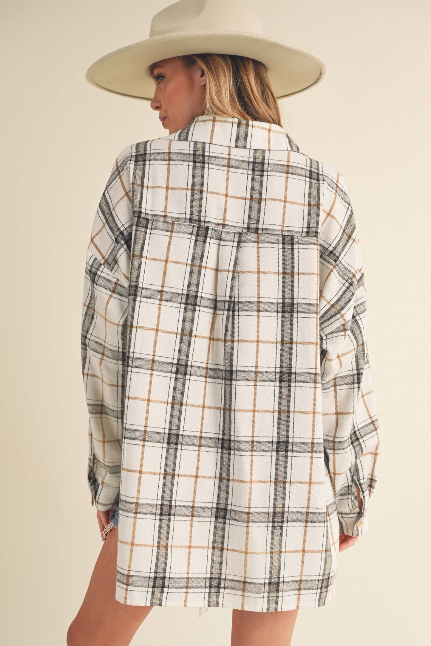 Person wearing a plaid shirt and beige hat on a plain background