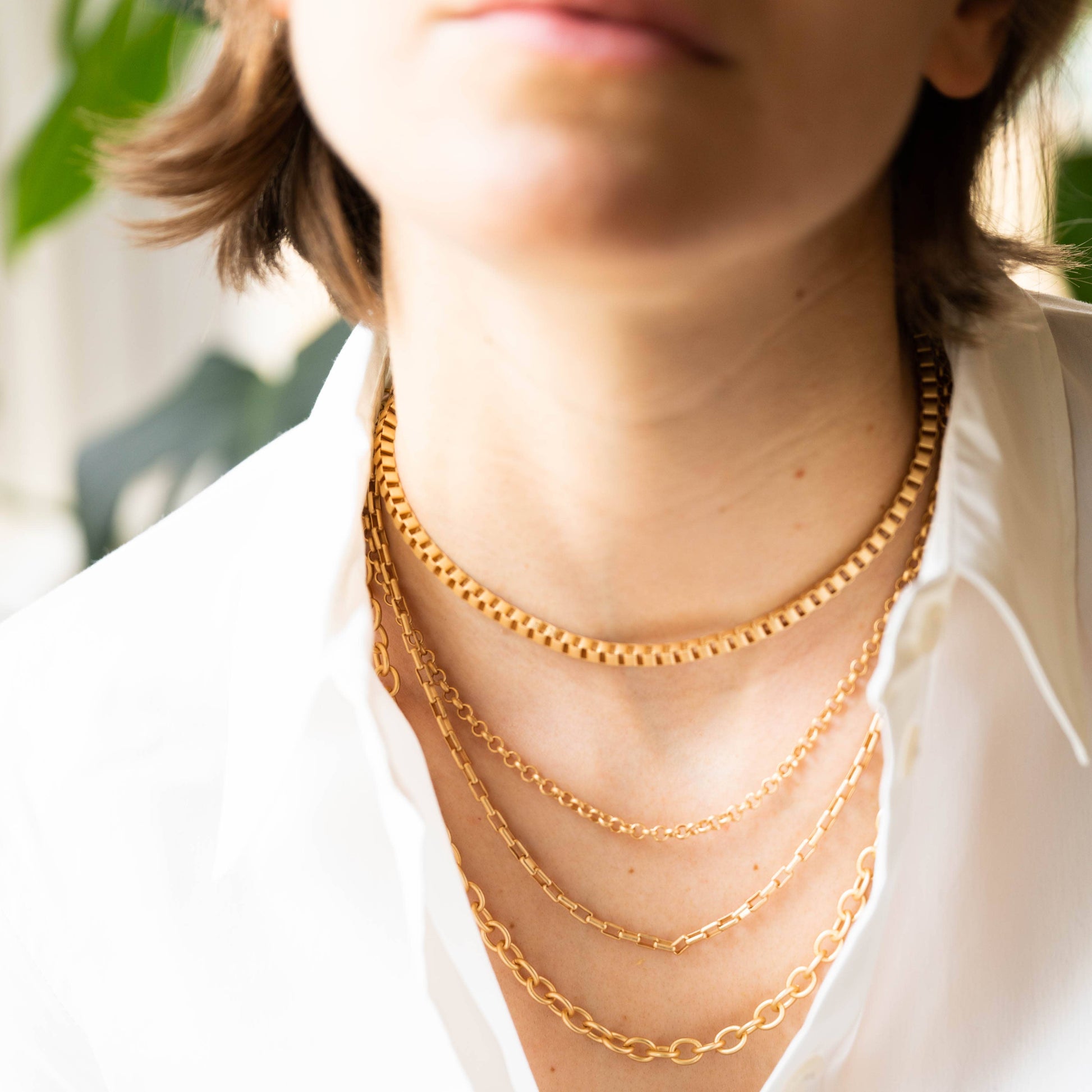 Close-up of a person wearing gold chain necklaces with a blurred background