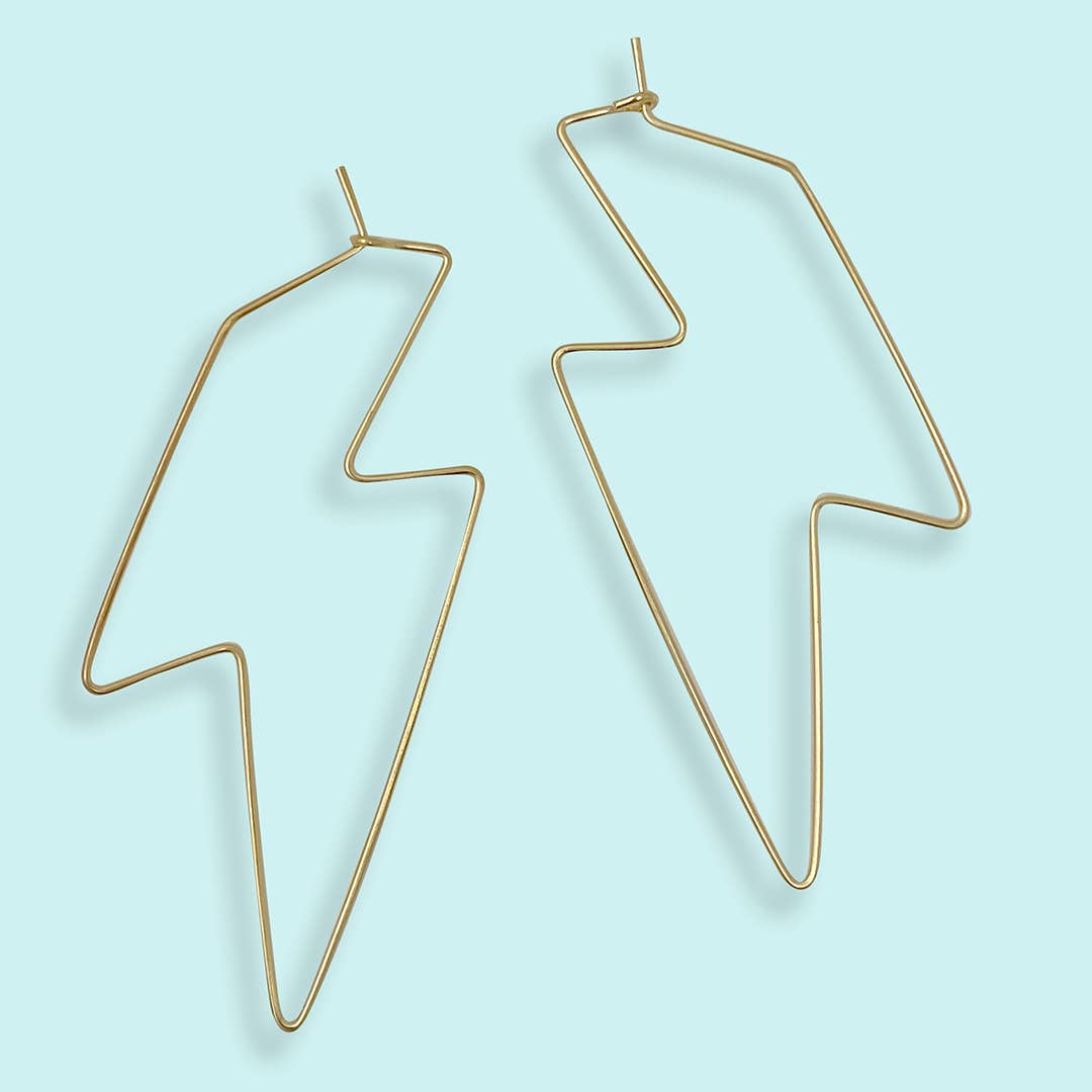 Gold geometric earrings on a light blue background