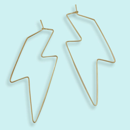 Gold geometric earrings on a light blue background
