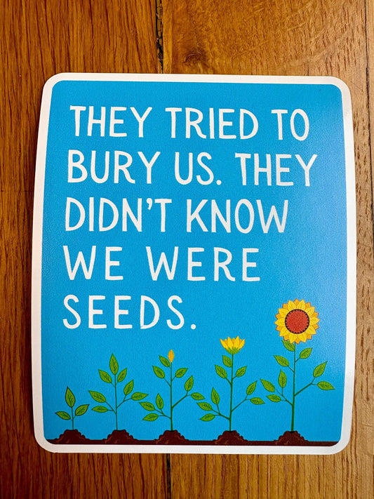 Blue sign with white text and sunflower illustration on a wooden surface