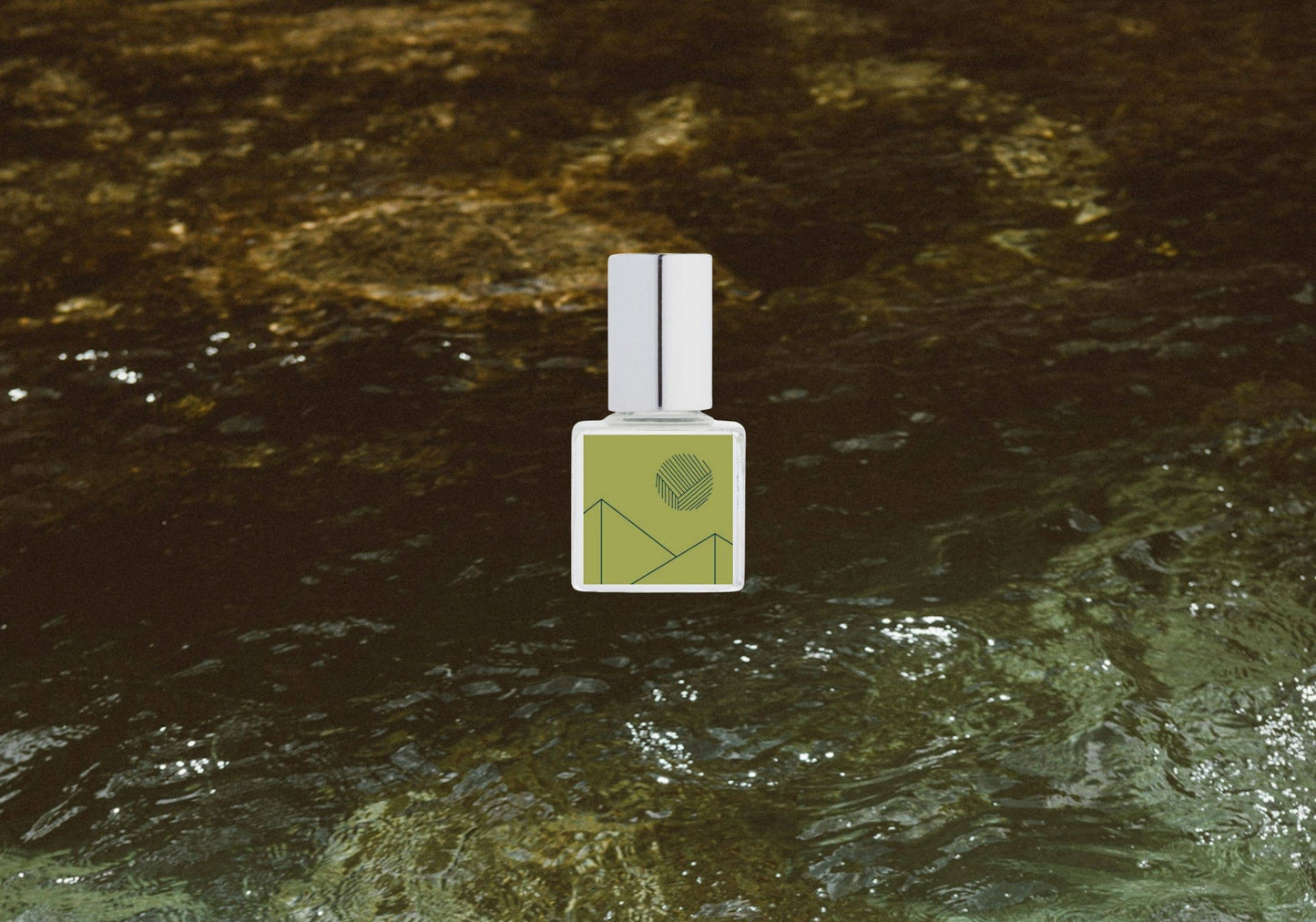 Fragrance bottle with green label on a textured brown surface