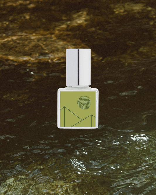 Fragrance bottle with green label on a textured brown surface