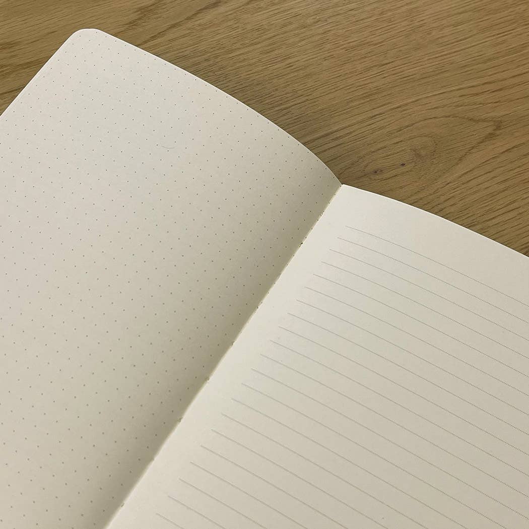 Open notebook with lined and dotted pages on a wooden surface