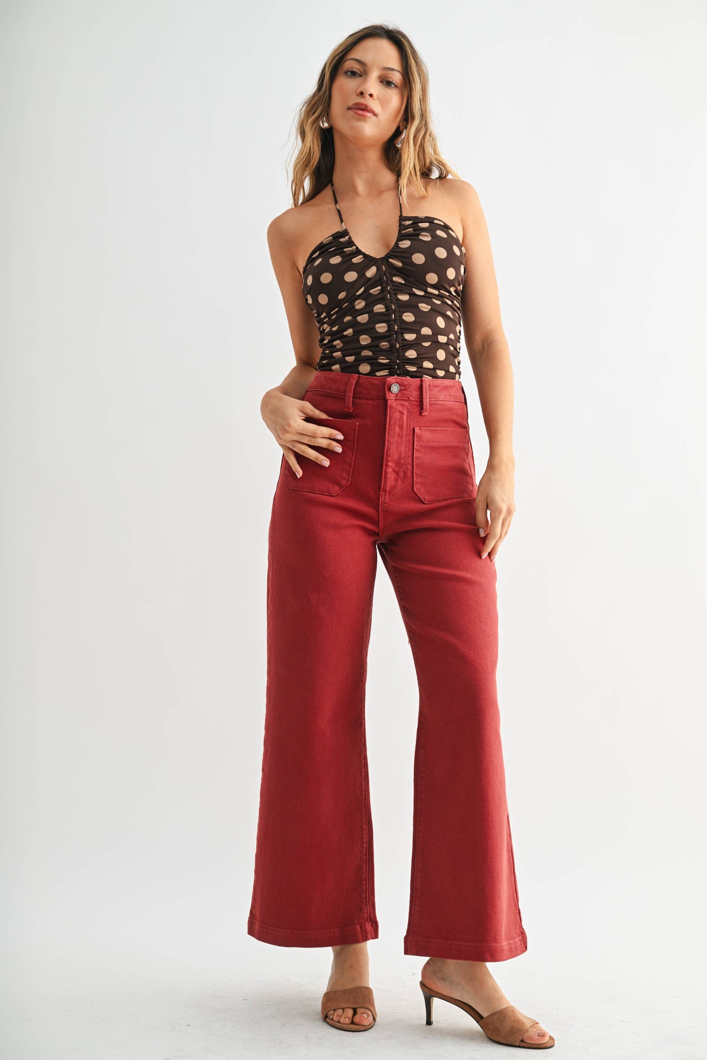 Woman wearing a black patterned top and red pants on a white background