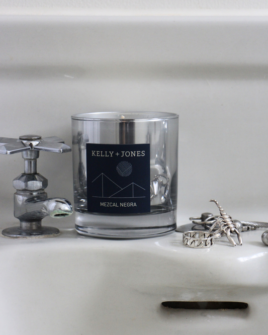 Glass candle with a label on a white surface next to a keychain and ring.