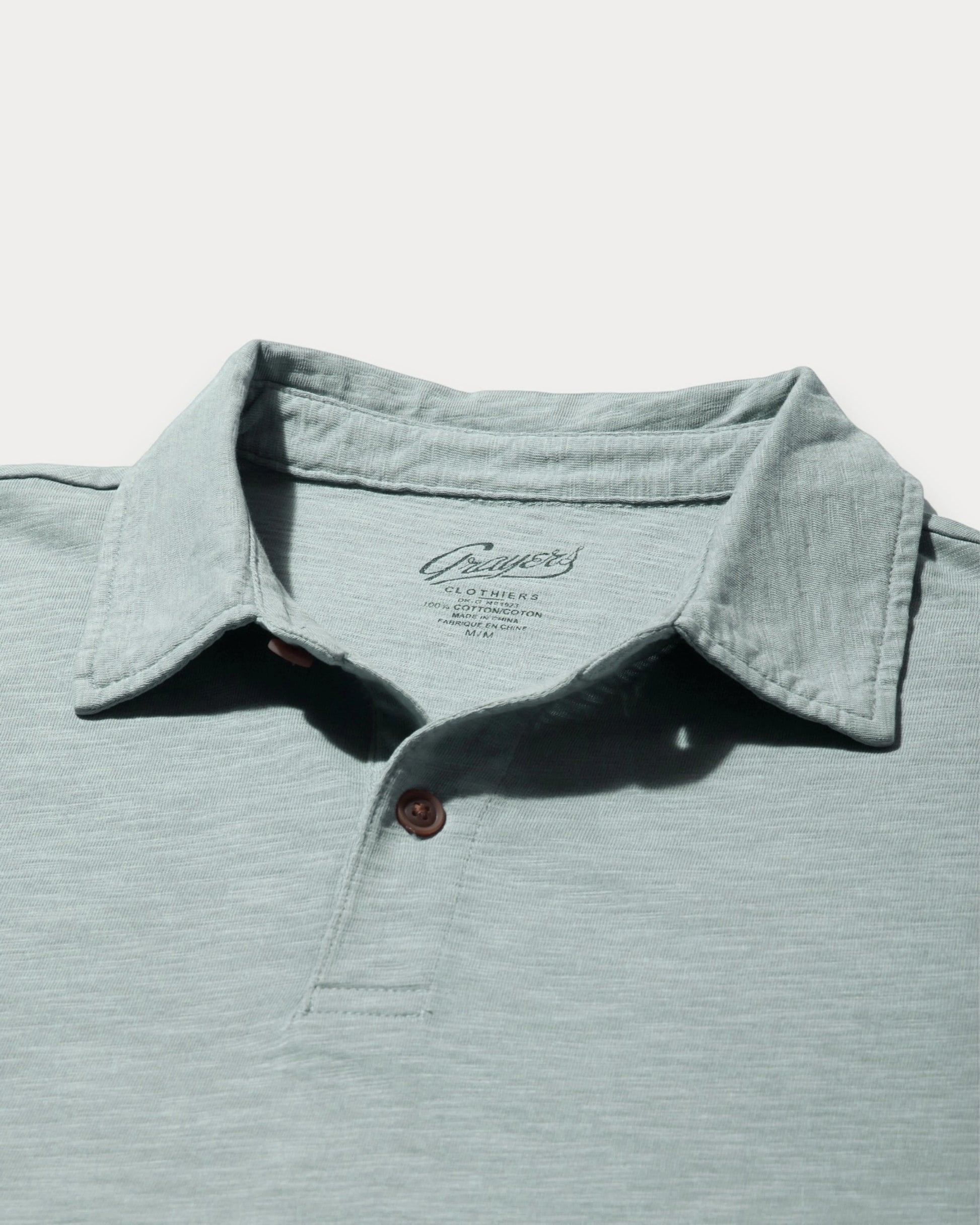 Light blue polo shirt with collar and button detail on a light gray background