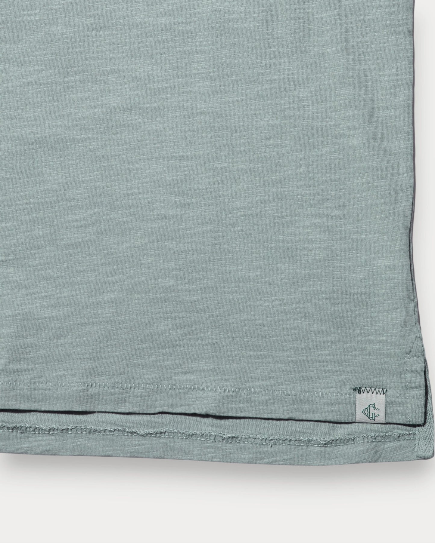 Close-up of a light blue fabric with a brand label on a white background