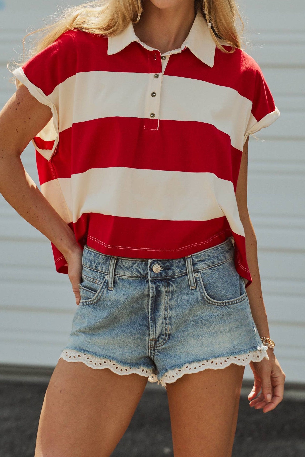 Woman wearing a red and white striped shirt with denim shorts against a neutral background