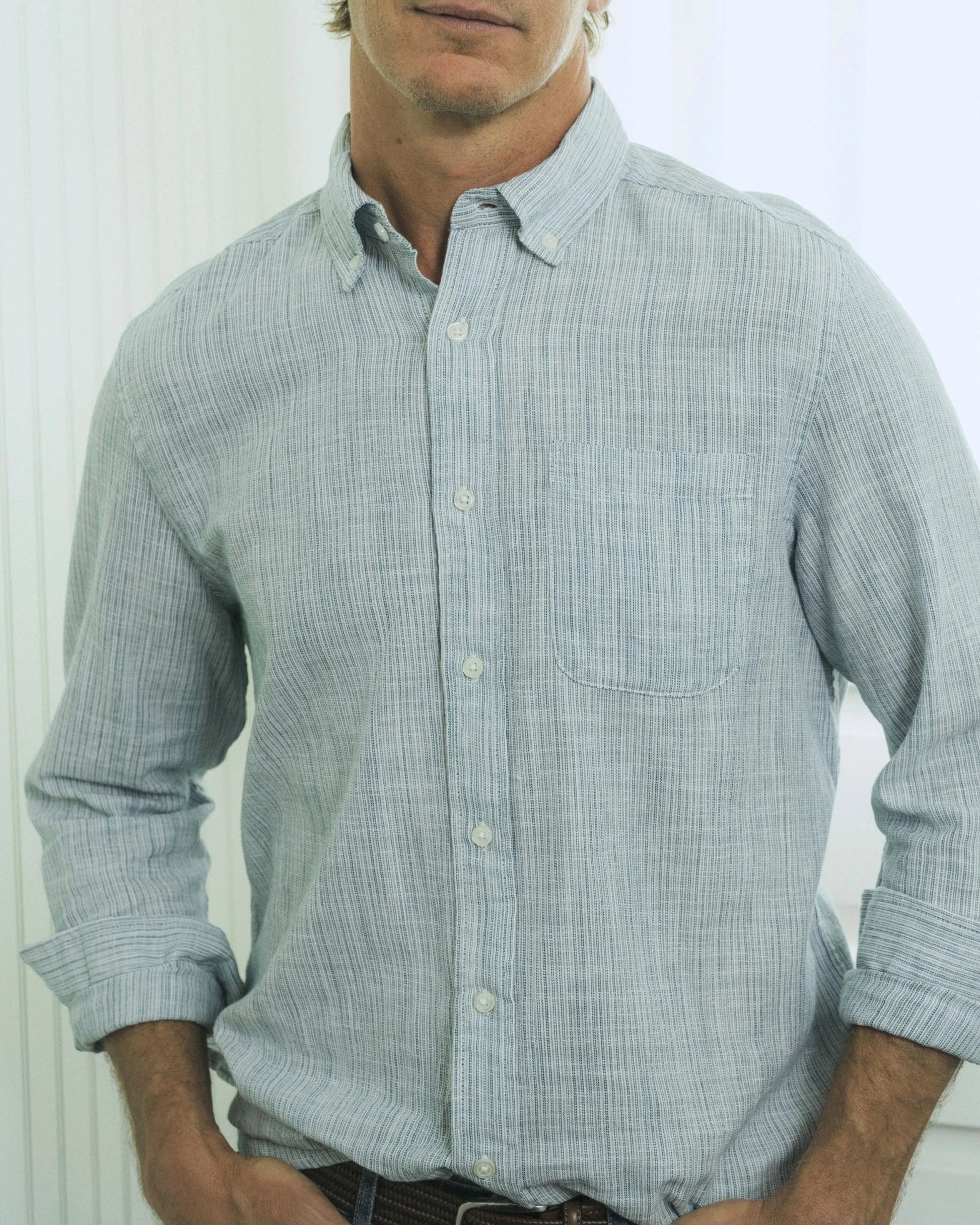 Man wearing a light blue checkered shirt against a white background