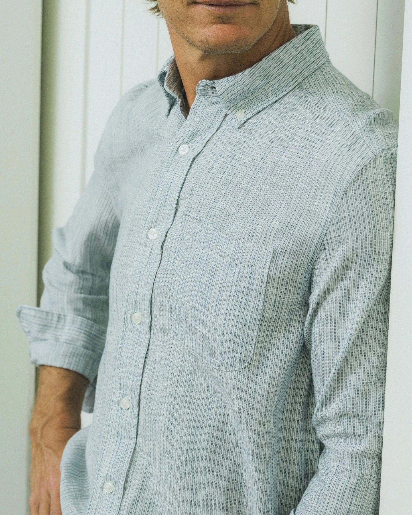 Man wearing a light blue checkered shirt against a white background