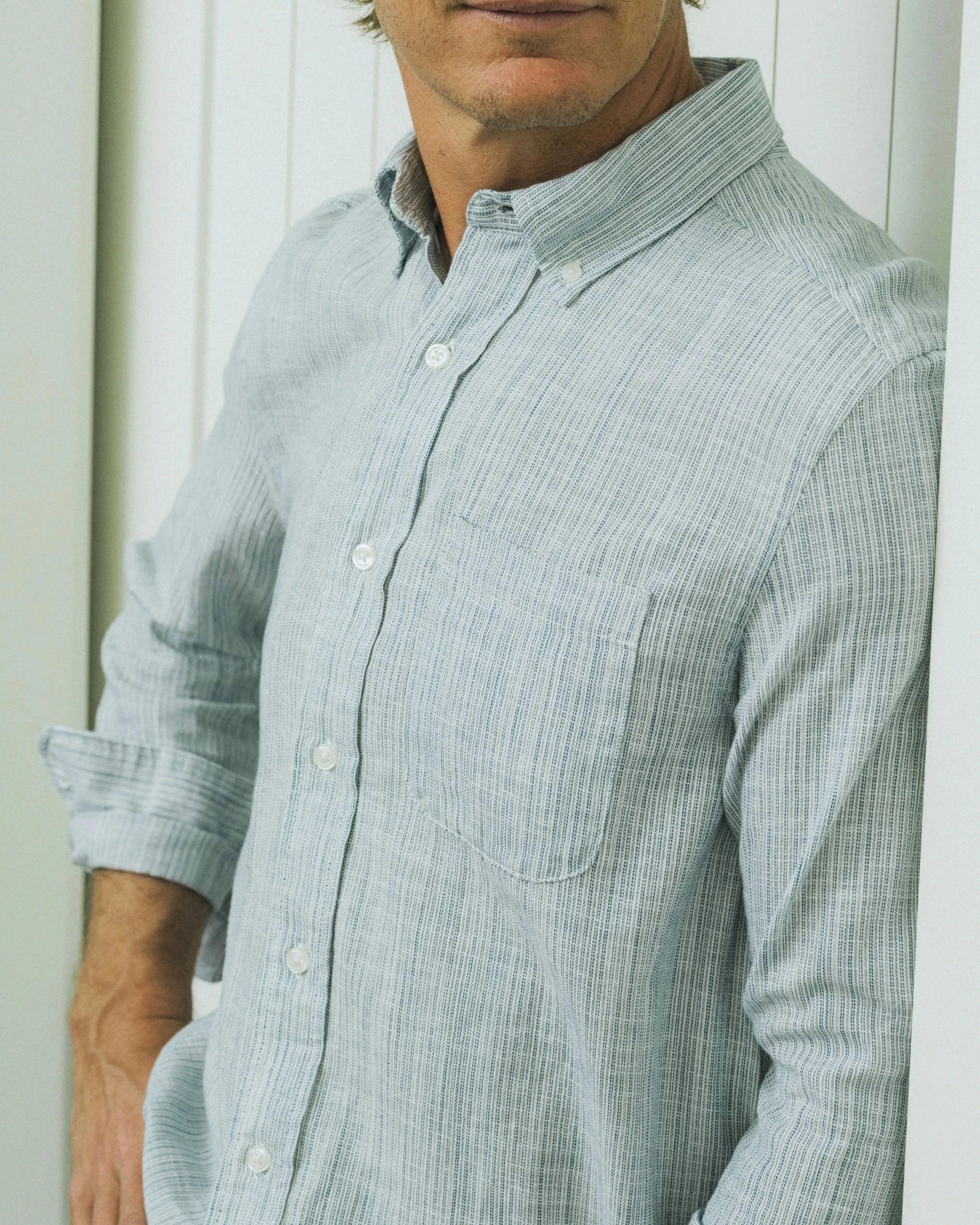 Man wearing a light blue checkered shirt against a white background