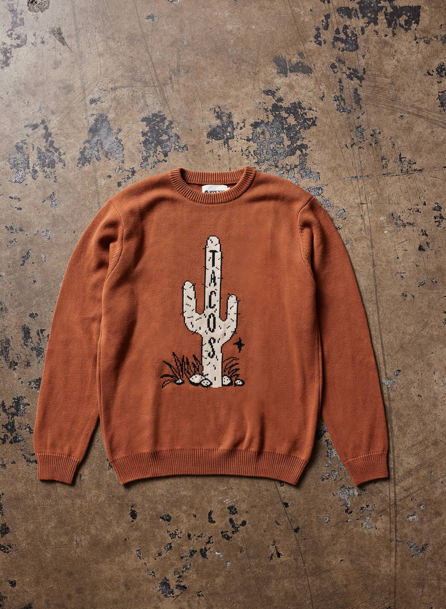 Brown sweater with cactus and 'TACOS' design on a textured brown background