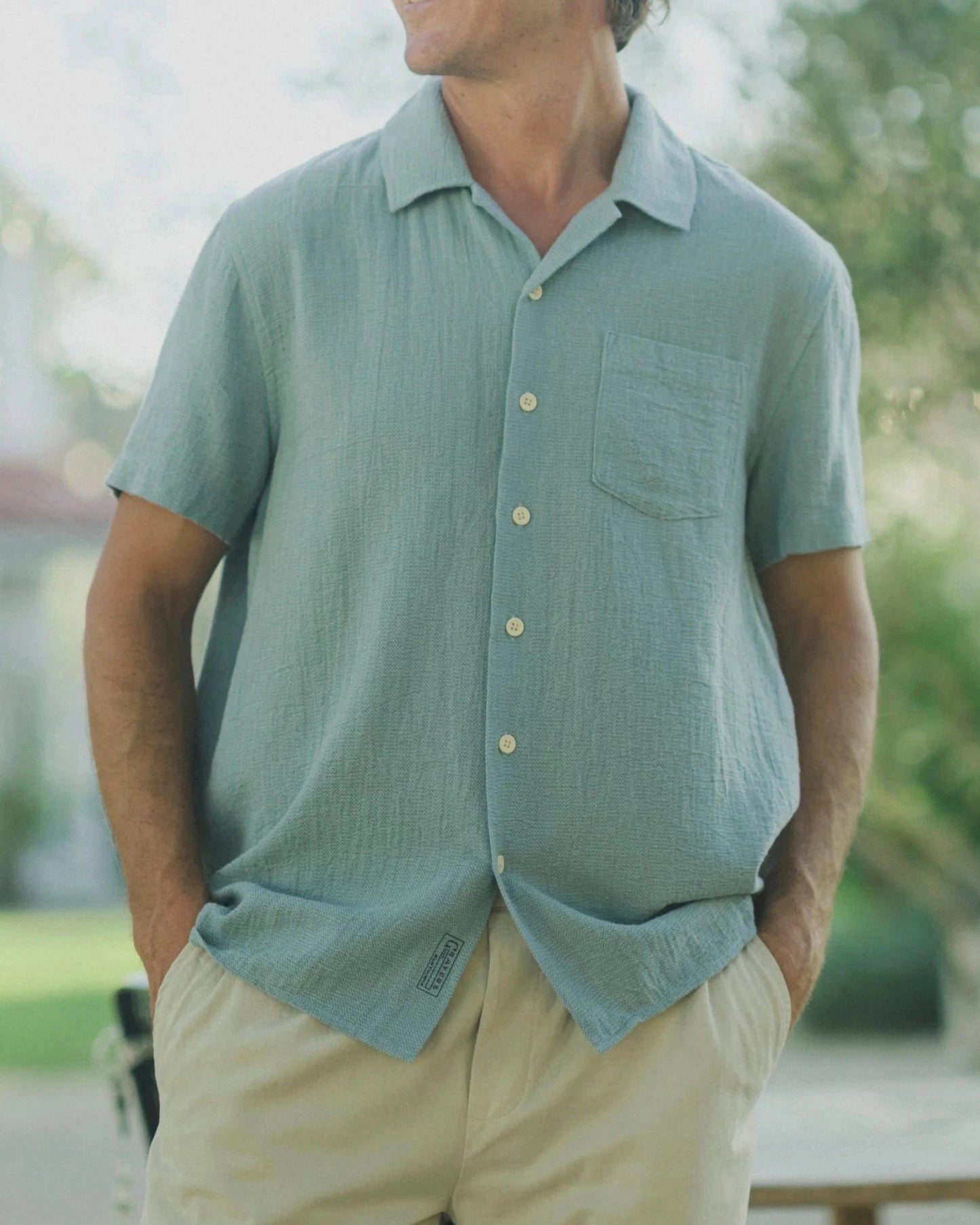 Man wearing sunglasses and a light blue shirt outdoors