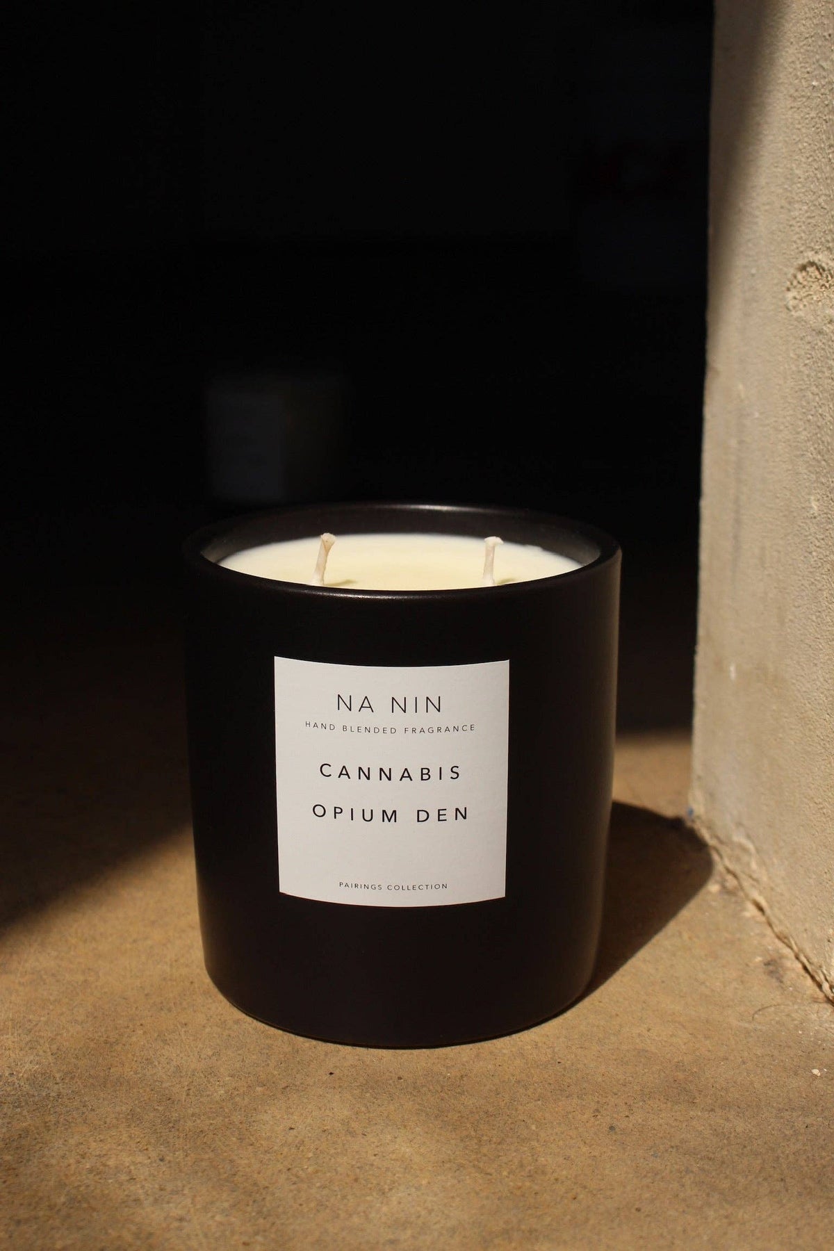 Black candle with a label on a textured surface