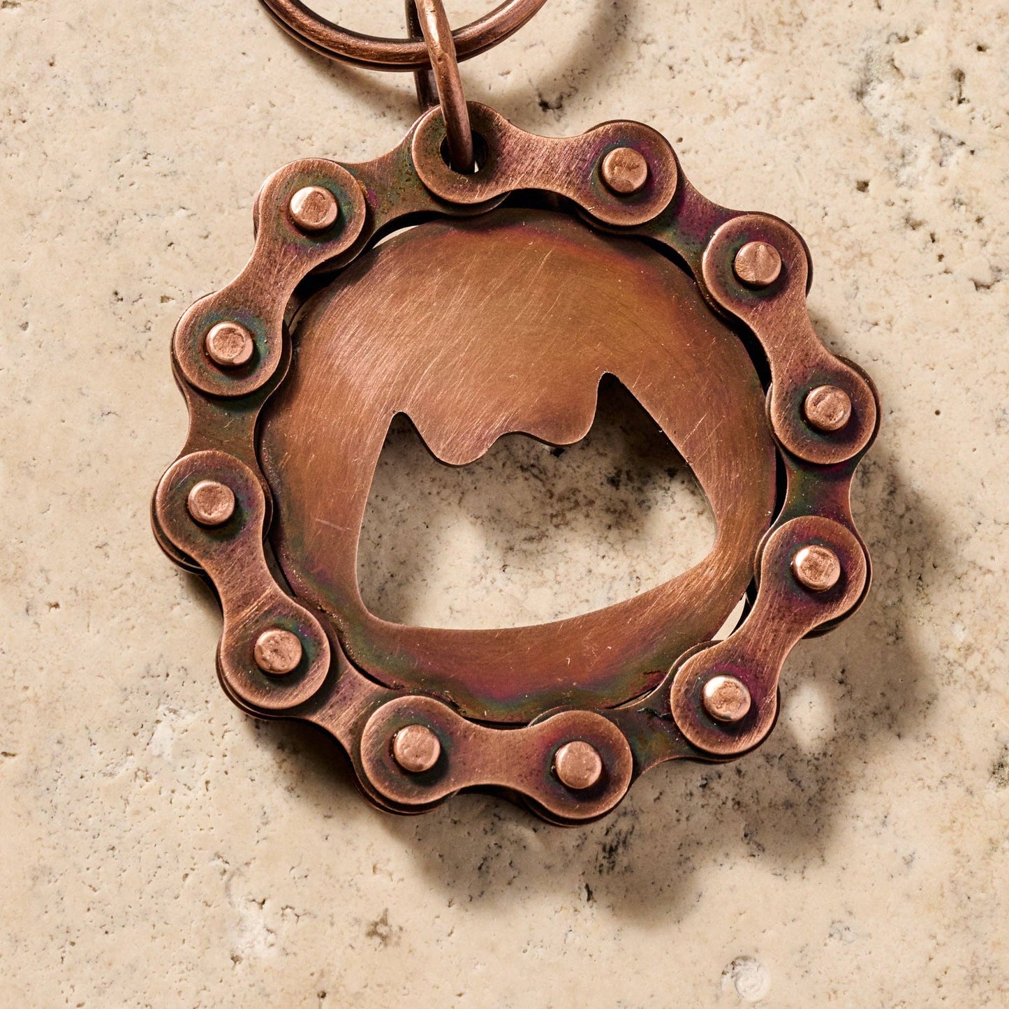 Copper bottle opener with chain design on a textured surface