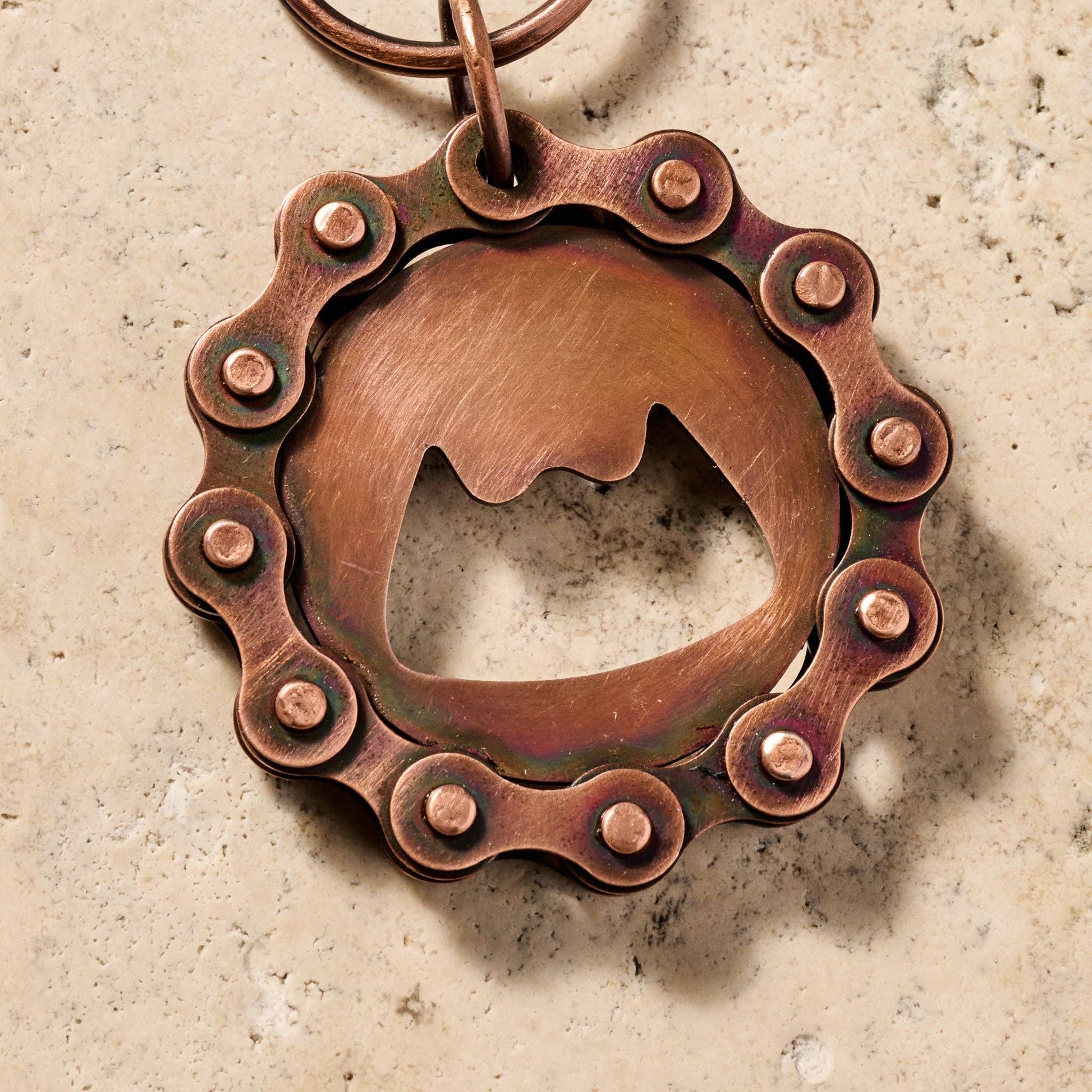 Copper bottle opener with chain design on a textured surface