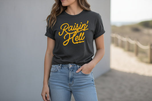 Black t-shirt with 'Raisin' Hell' text, paired with jeans and shoes on a light wooden surface.
