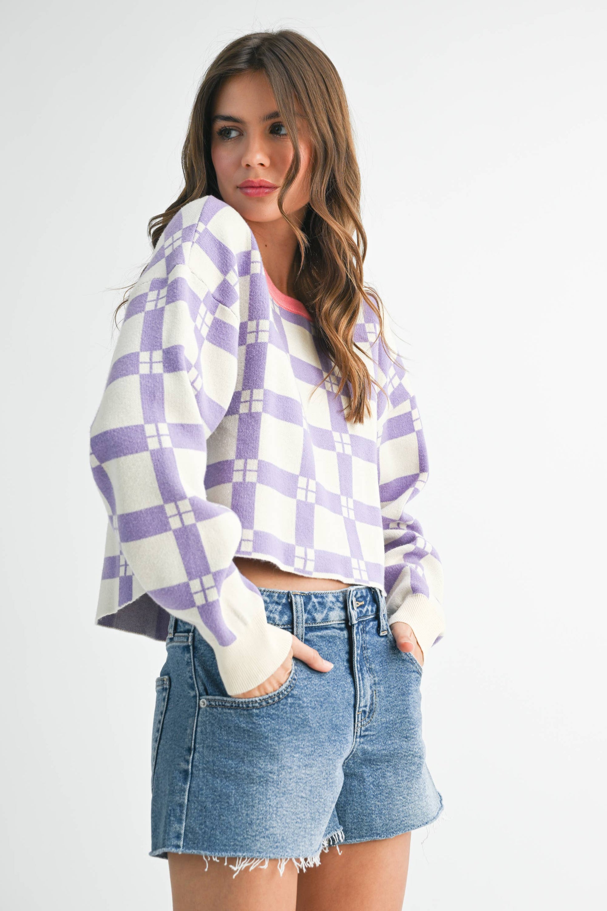Woman wearing a purple and white checkered shirt with denim shorts on a white background