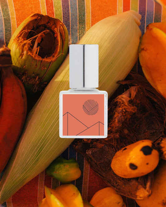 Perfume bottle with fruit and corn on a colorful striped background