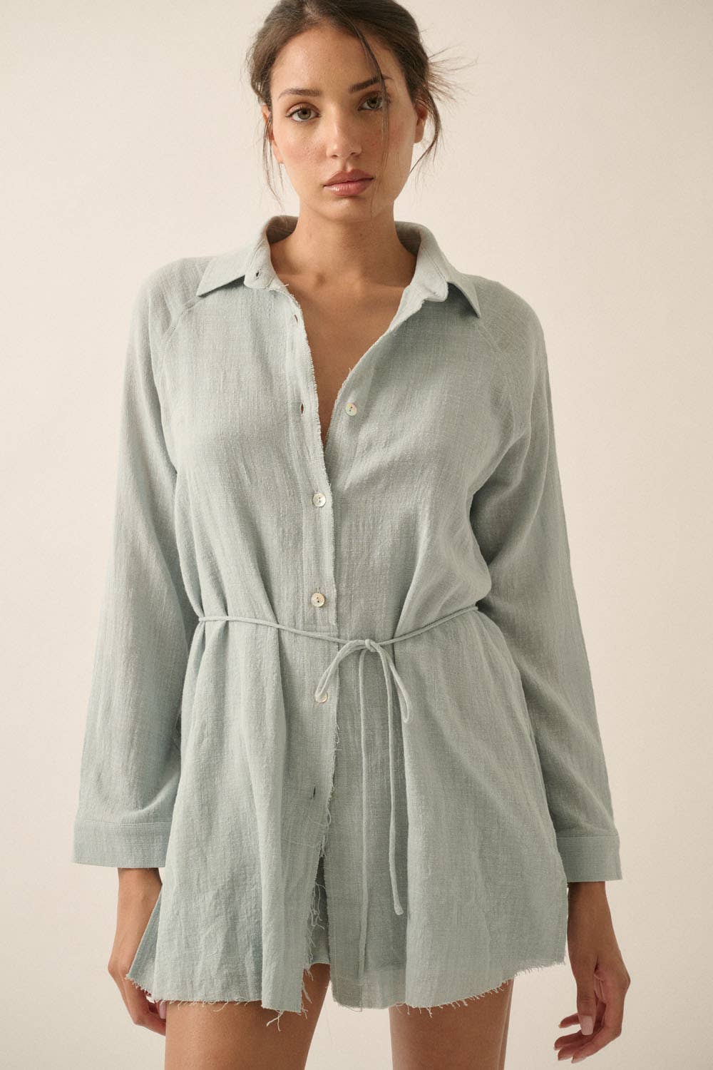 Woman wearing a light green shirt dress against a plain background