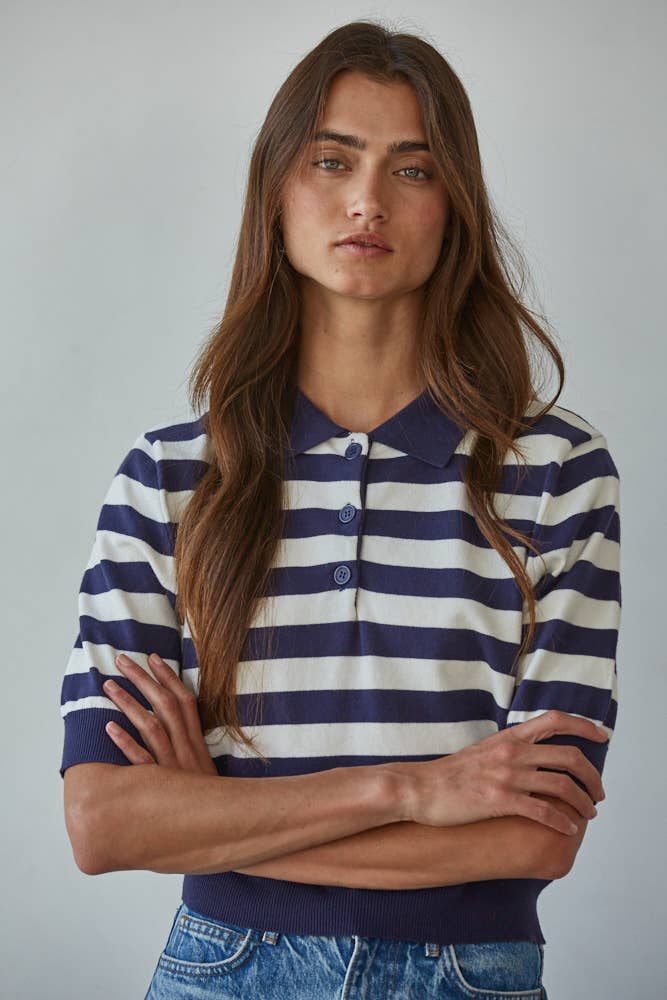 Woman wearing a navy and white striped shirt with blue jeans against a gray background