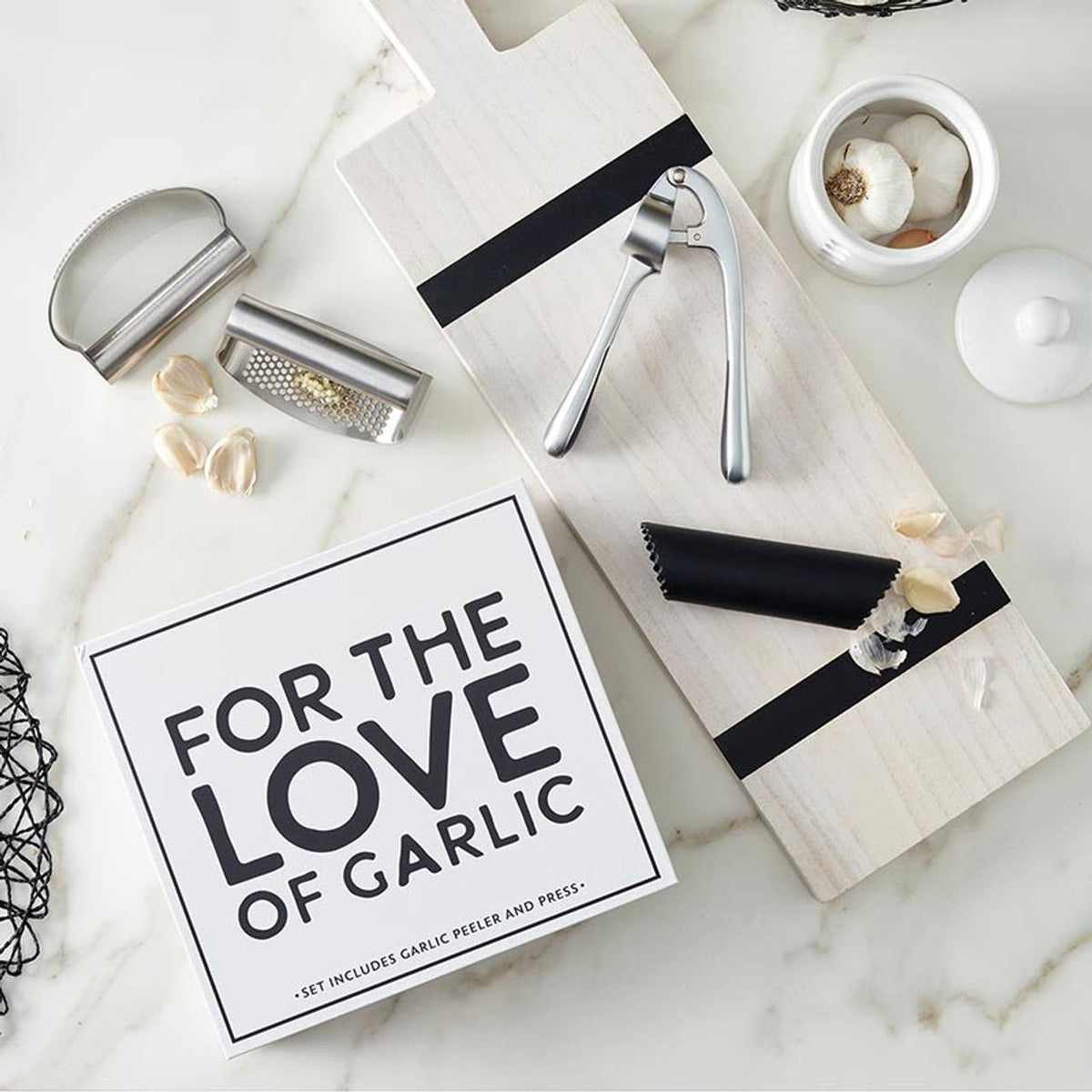 Garlic peeler set with a sign reading 'For the Love of Garlic' on a marble surface.