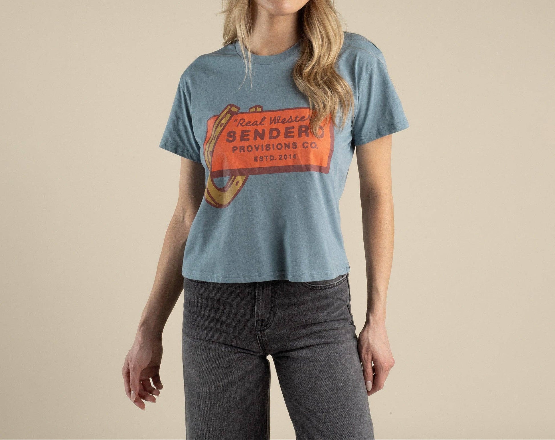 Woman wearing a blue t-shirt with a red and orange logo on a beige background