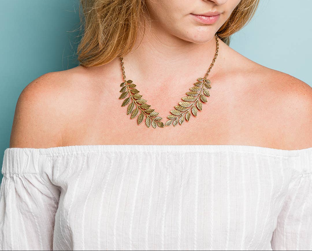 Woman wearing a leaf-shaped necklace against a light blue background
