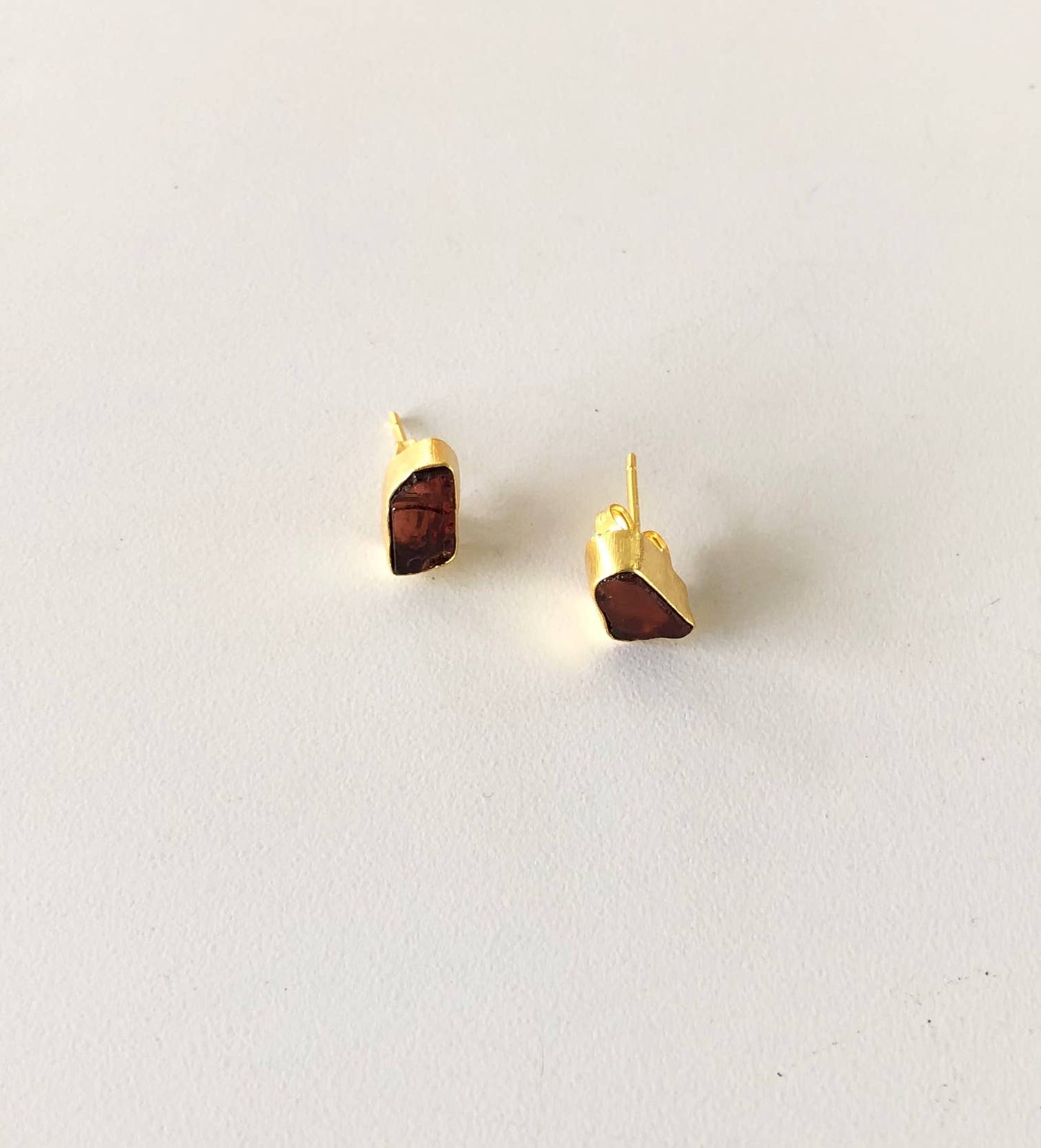 Gold earrings with brown stone accents on a light gray background