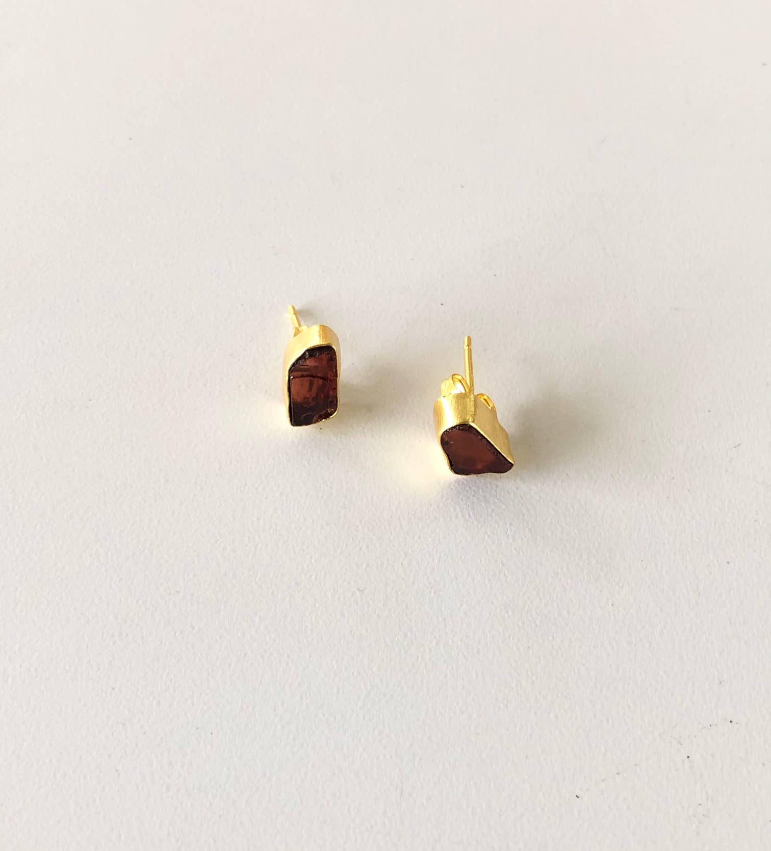 Gold earrings with brown stone accents on a light gray background