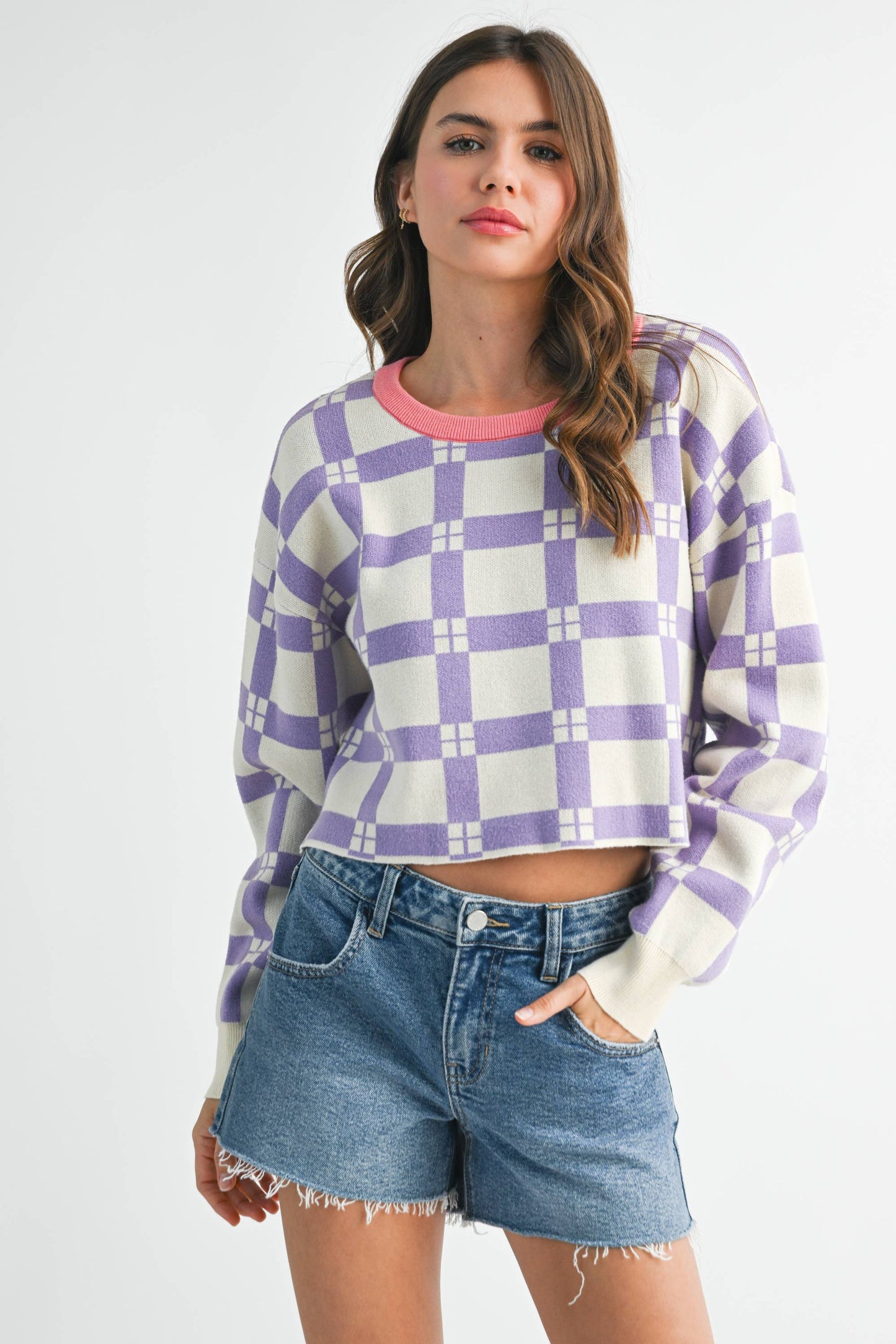 Woman wearing a checkered sweater and denim shorts on a white background