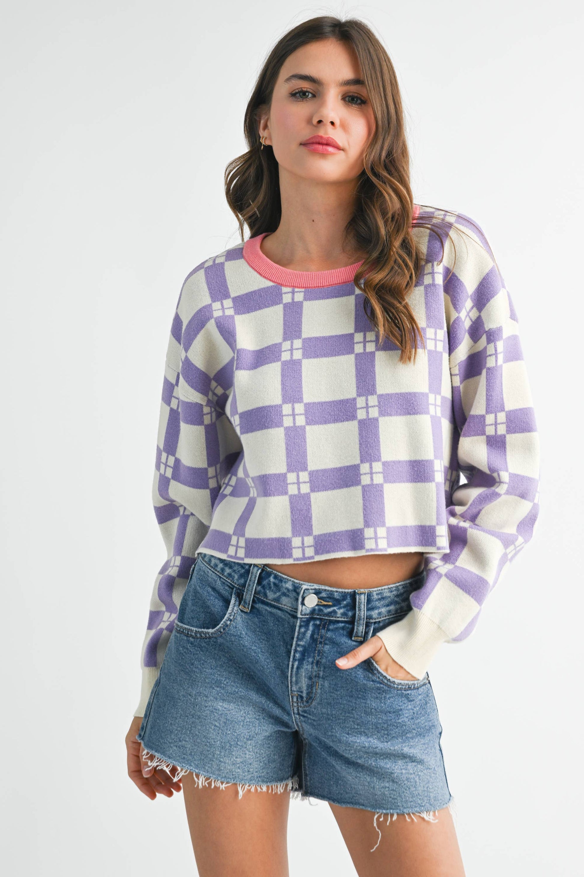 Woman wearing a checkered sweater and denim shorts on a white background