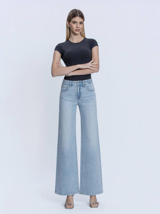 Woman wearing a black top and light blue jeans on a white background
