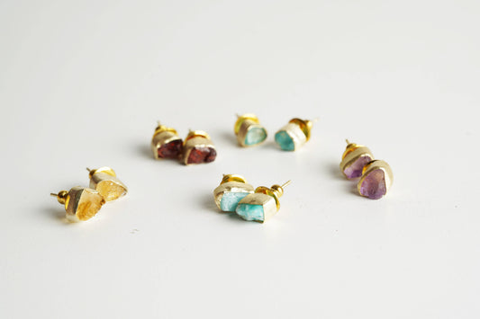 Gold-framed gemstone stud earrings on a light gray background