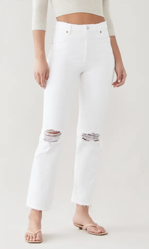 A person standing wearing high-rise straight leg white jeans with signature back pocket stitching and a zip closure.
