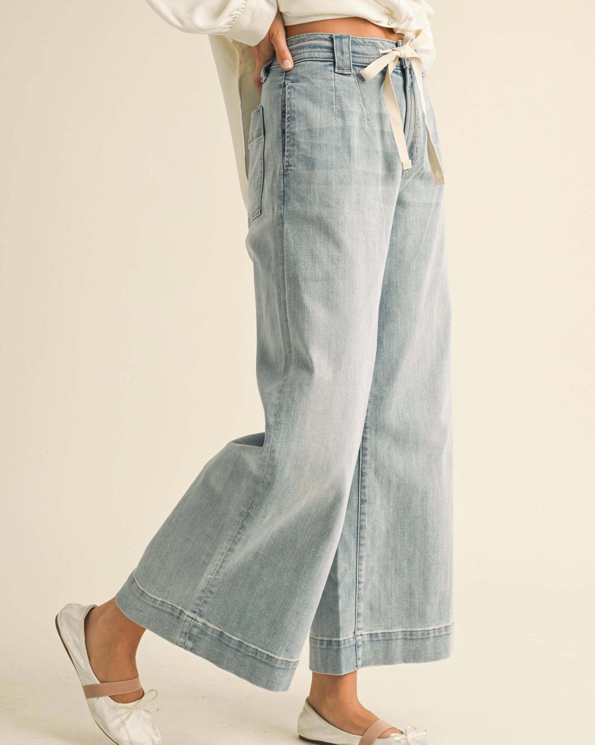 Light blue denim pants worn by a person on a beige background