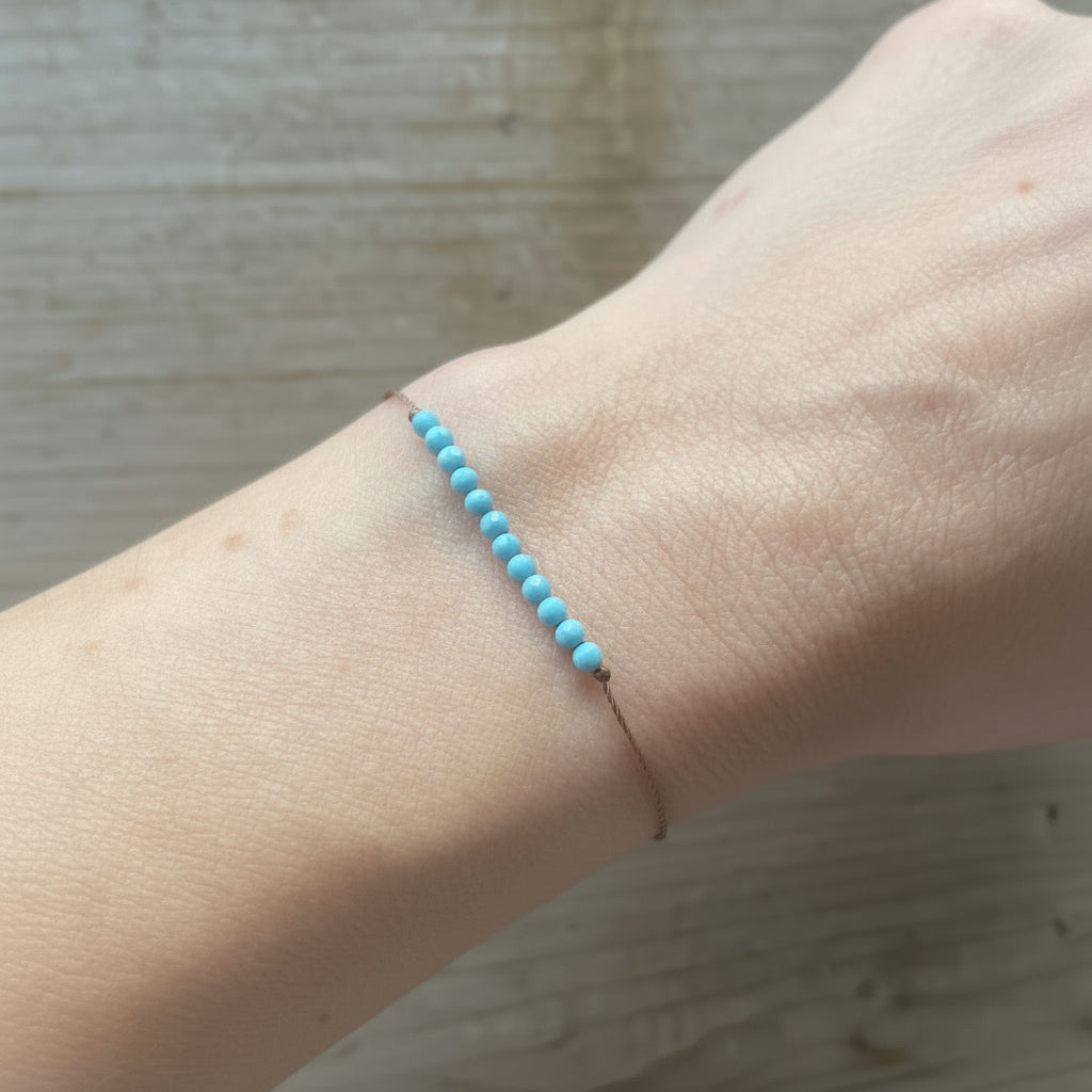 Turquoise beaded bracelet on a wrist with a neutral background