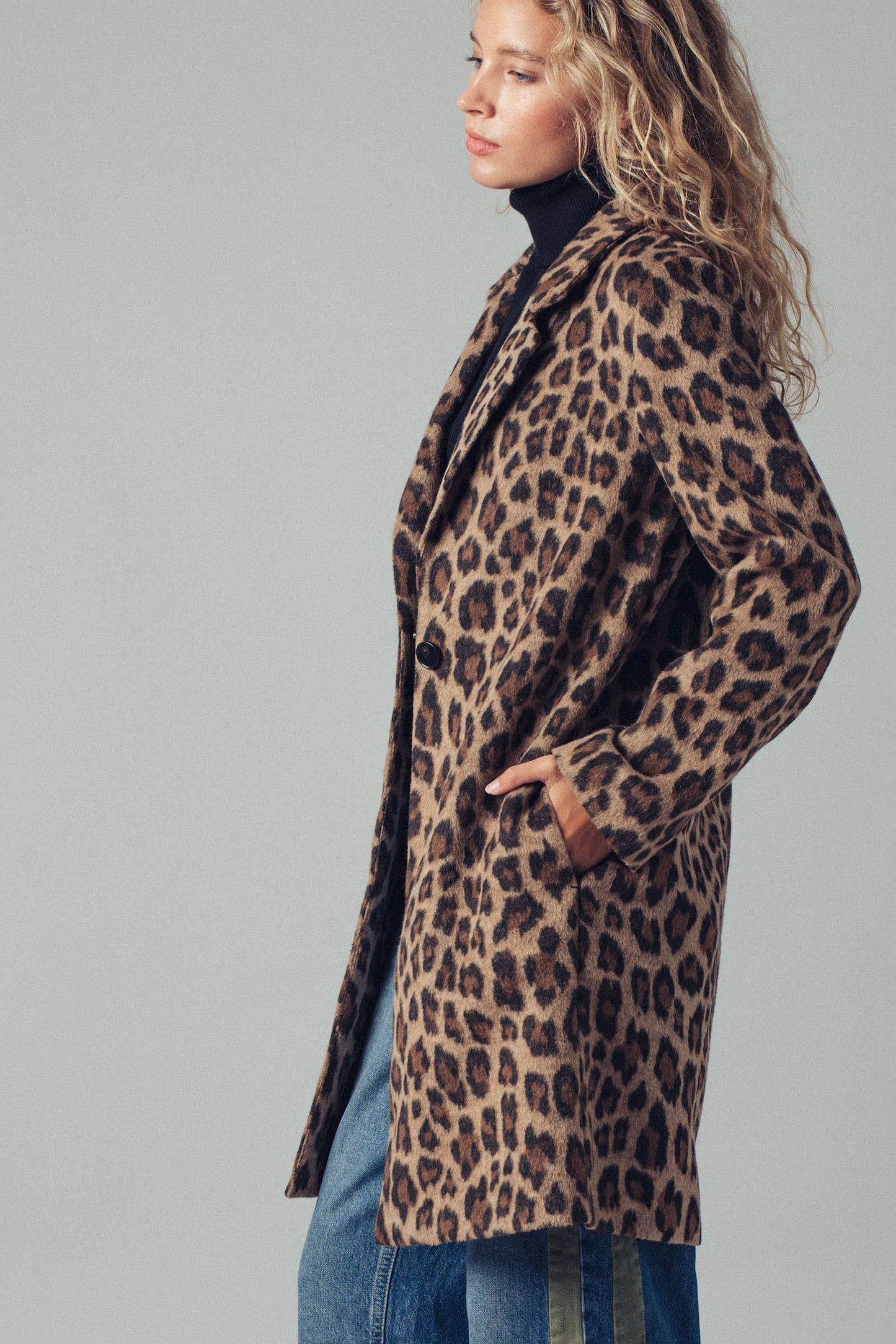 Person wearing a leopard print coat on a gray background