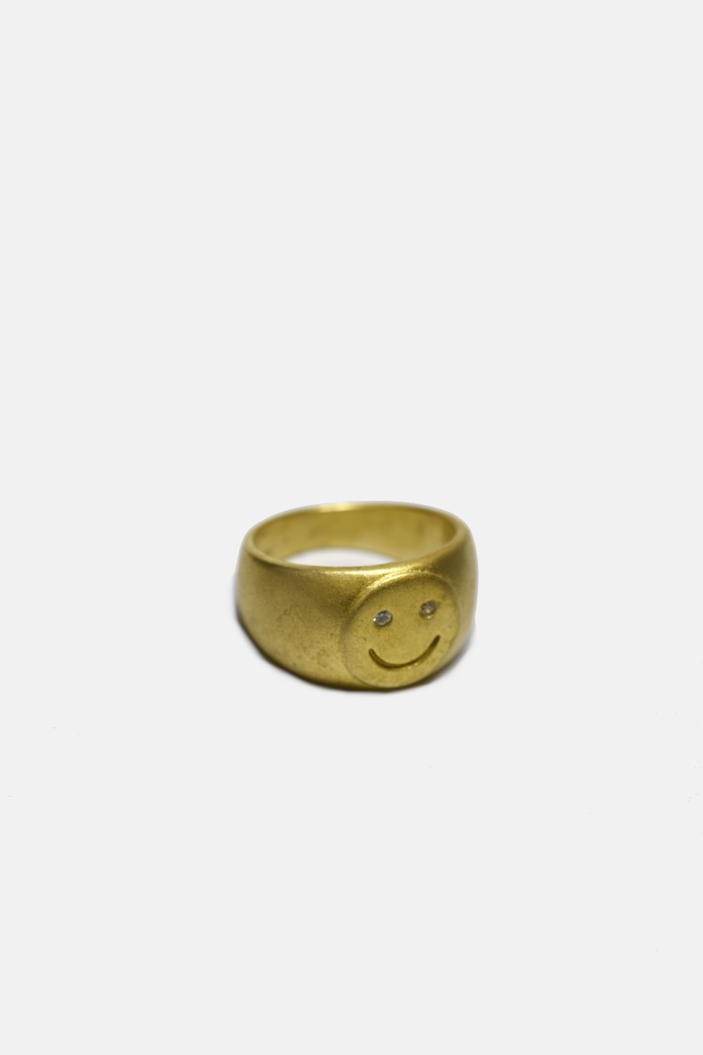 Gold smiley face ring on a white background
