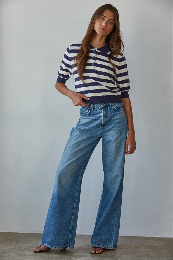 Woman wearing a striped sweater and blue jeans against a plain background