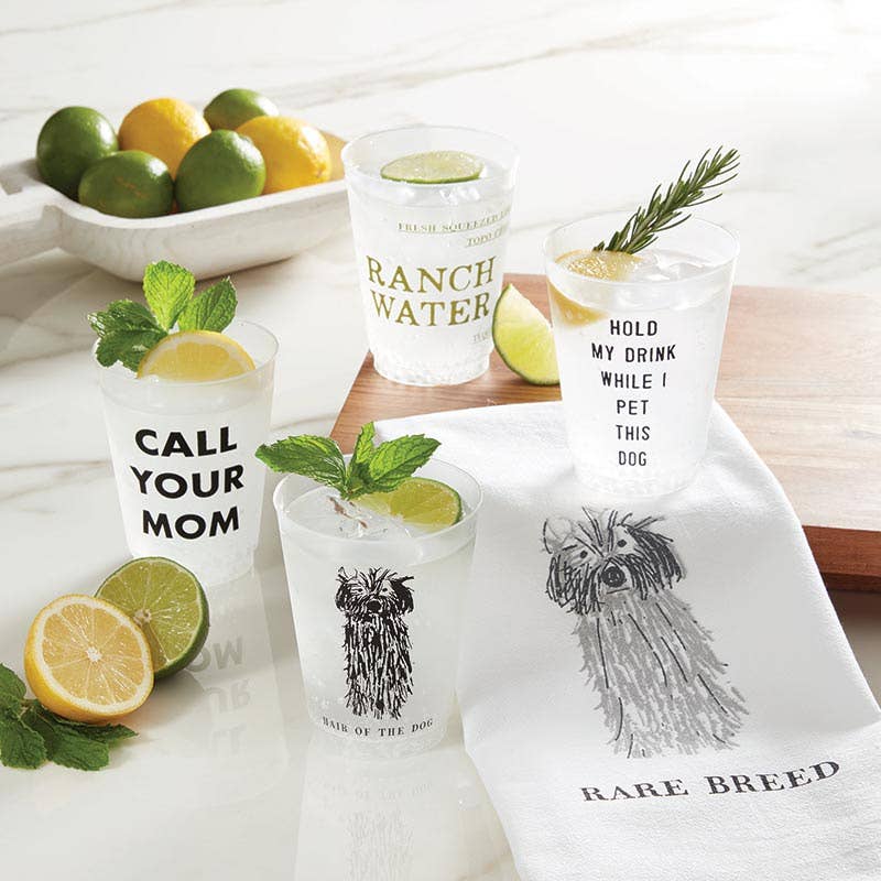 Clear glasses with humorous text designs on a white surface with lemons and limes.
