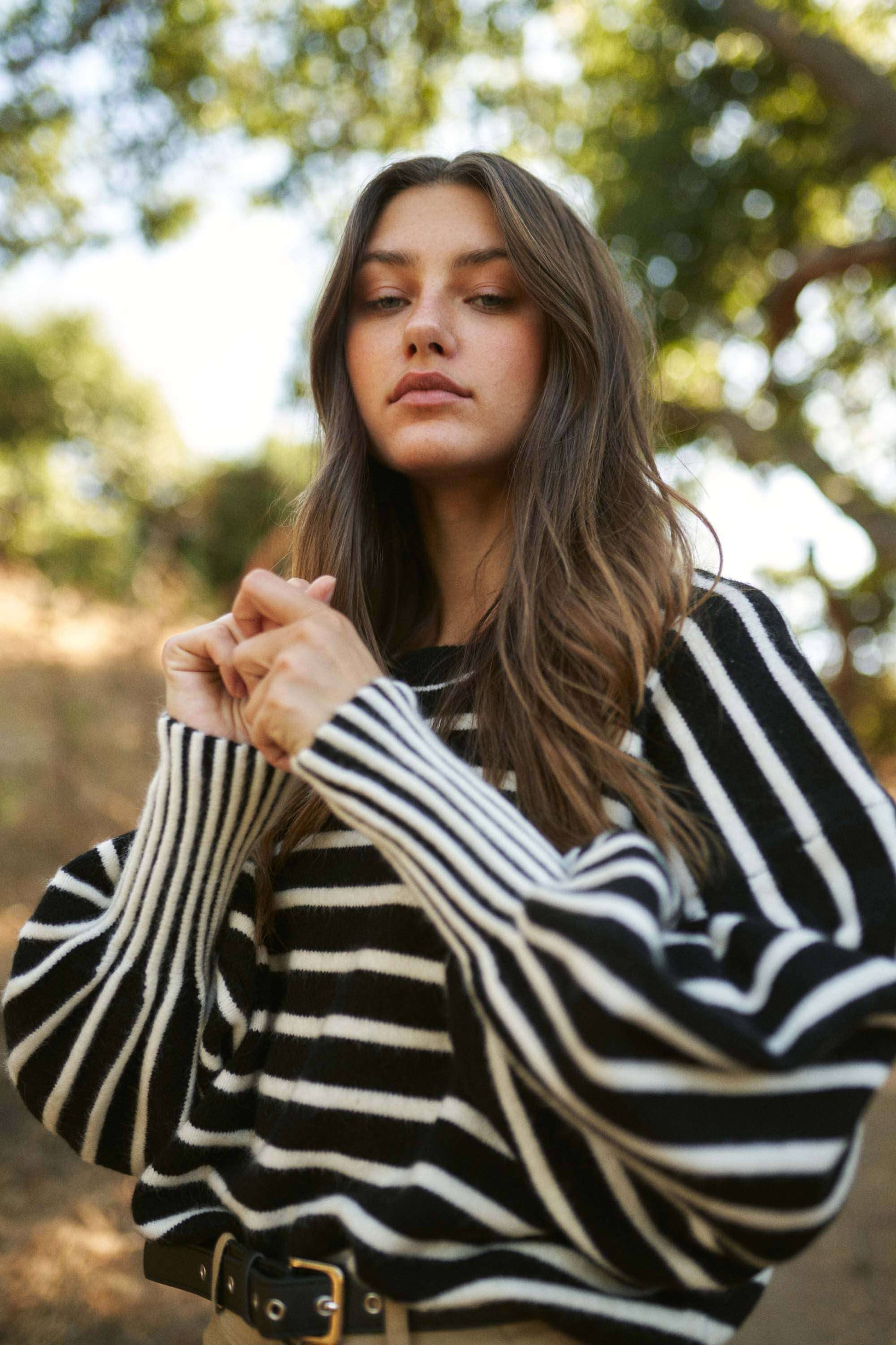 Woman wearing a black and white striped sweater with a blurred natural background