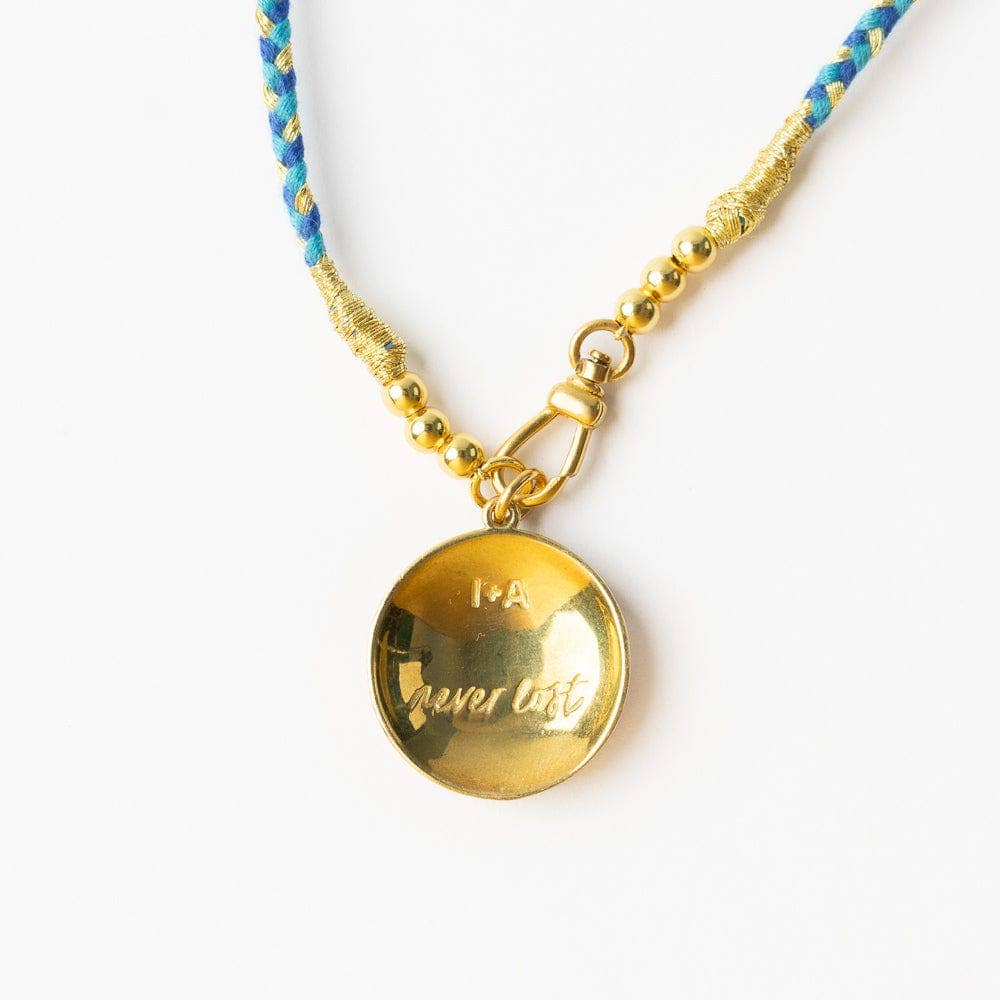 Gold necklace with a round pendant on a white background