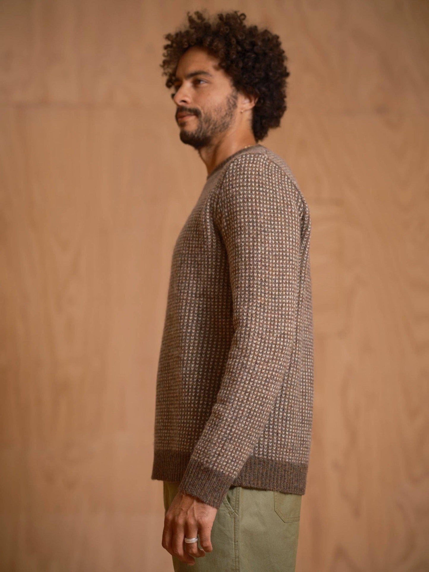 Man wearing a patterned sweater against a wooden background