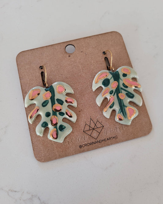 Pair of leaf-shaped earrings on a cardboard backing with a brand logo.