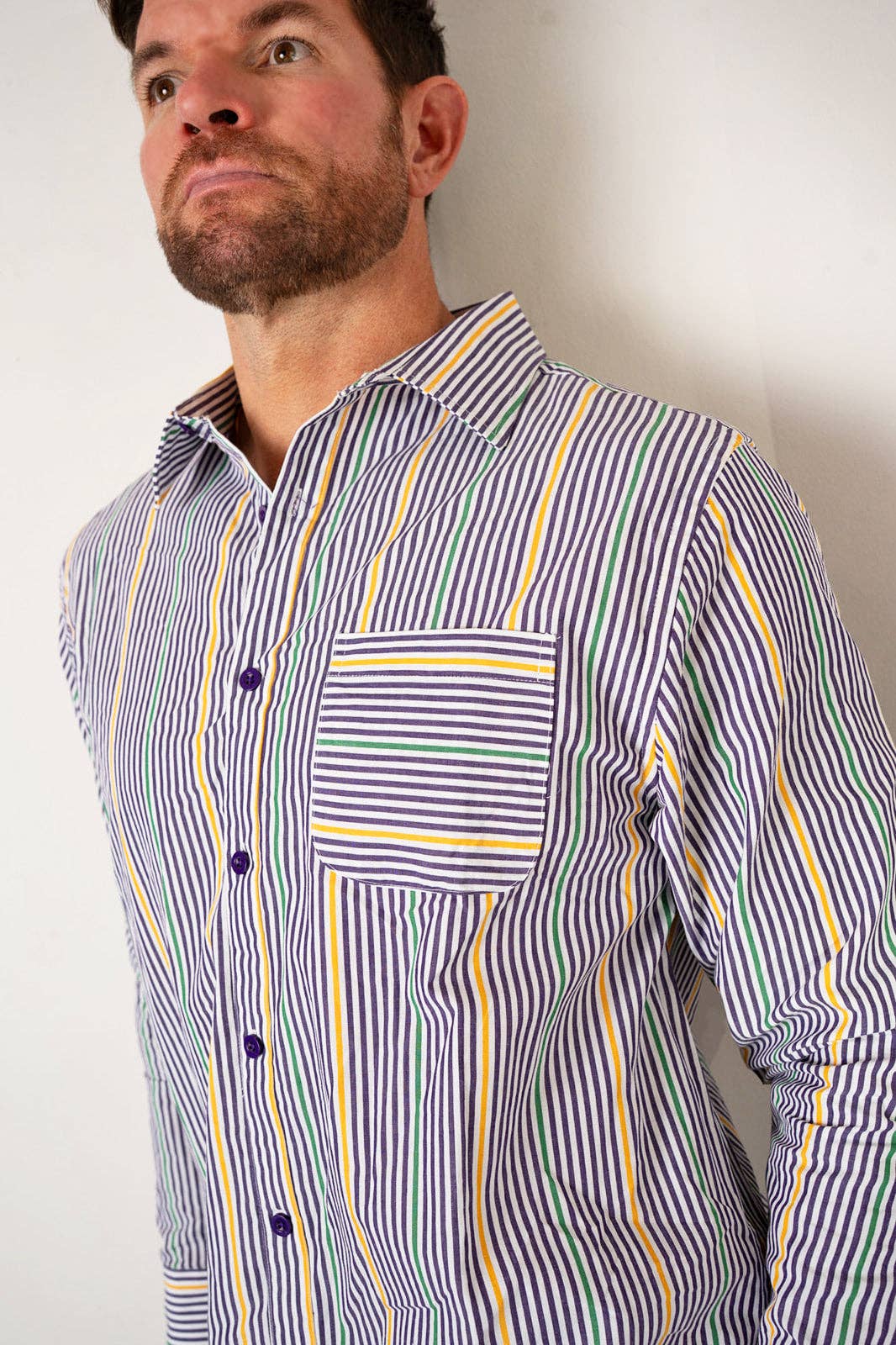 Man wearing a striped shirt with vertical yellow and blue lines on a plain background