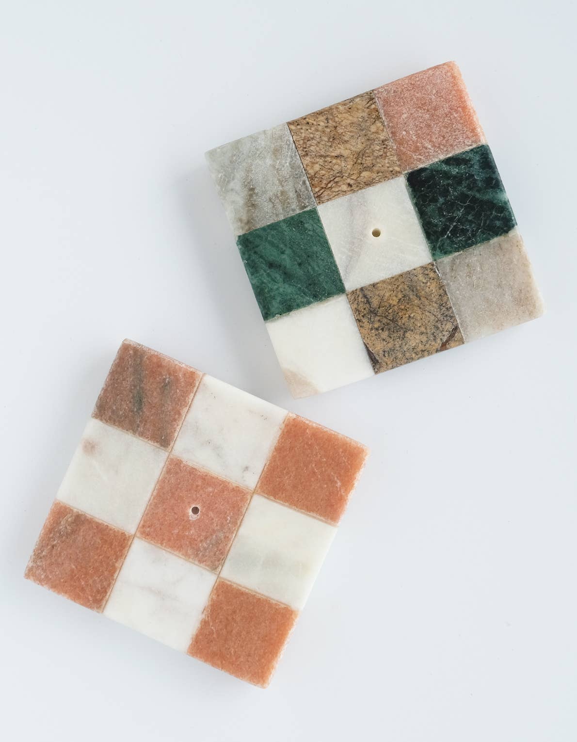 Two square marble coasters with a checkered pattern on a white background